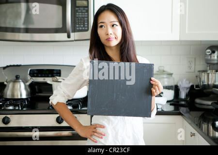 Jeune femme black board in kitchen Banque D'Images