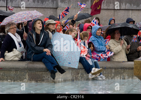 Jubilé de diamant de la Reine 2012 – les fêtards avec des parapluies à l’abri de la pluie près de la fontaine à Trafalgar Square, Londres, pendant les célébrations Banque D'Images