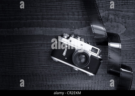 Retro style caméra sur un plateau de table en bois avec des bandes de film surexposé 35 Banque D'Images