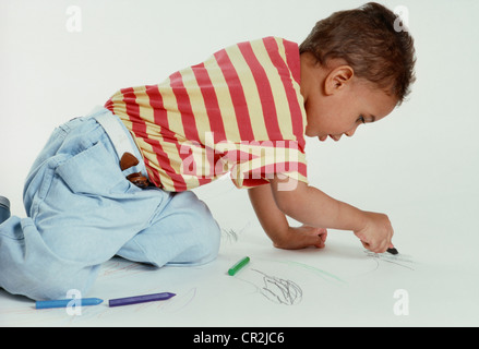 Trois ans mixed race boy avec des crayons à colorier. Banque D'Images