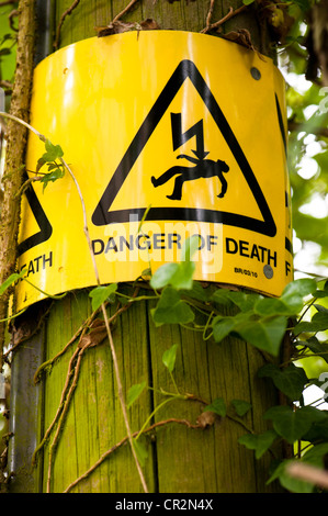 Danger de mort par électrocution avertissement sur un poteau en bois Banque D'Images