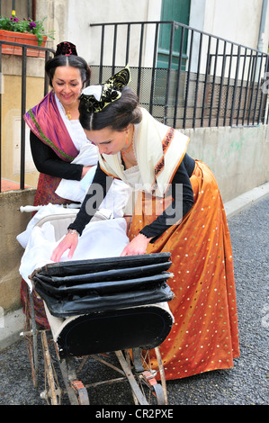 Mesdames en costume traditionnel lors de la 500ème année de Fete de tuteurs, à Arles à la recherche à un bébé dans une période la pram Banque D'Images