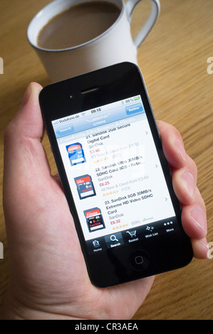 À l'aide d'un iPhone 4G téléphone intelligent pour acheter des produits de l'électronique de Amazon.com boutique en ligne Banque D'Images