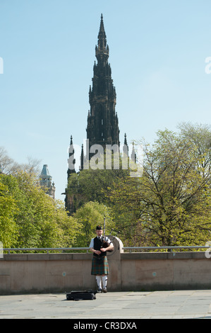 Piper jouant à Édimbourg avec le monument Scott en arrière-plan, Écosse Banque D'Images