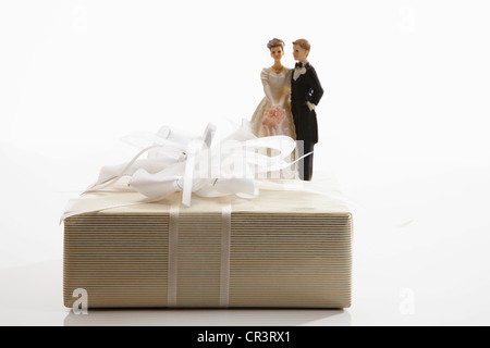 Cadeau de mariage, cadeau avec un arc blanc et un couple mariée miniature Banque D'Images