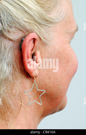L'aide auditive moderne petit derrière l'oreille d'une femme, de 55 à 60 ans, d'oreille, dureté d'oreille Banque D'Images