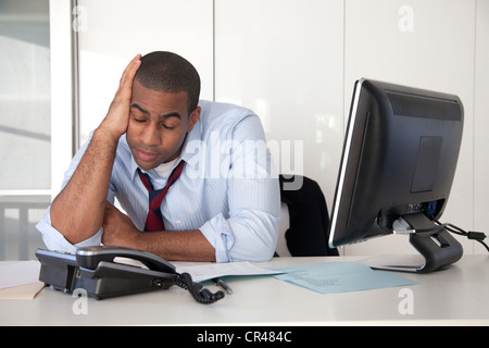 Fatigué Black businessman sitting at desk Banque D'Images