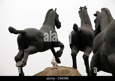 C'est une photo de statues de chevaux faits à partir du fer ou d'acier ou de cuivre. Ils sont debout sur un gros rocher au milieu d'une ville. Ils courent Banque D'Images