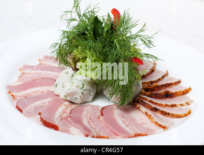 Morceaux de jambon et de bacon sur une plaque blanche avec un faisceau de vert Banque D'Images