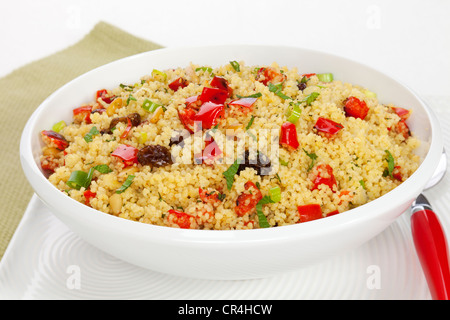 Salade de couscous, avec des poivrons rouges, des raisins secs, les pignons, l'oignon vert et de la menthe. Shallow DOF, se concentrer sur le centre. Banque D'Images