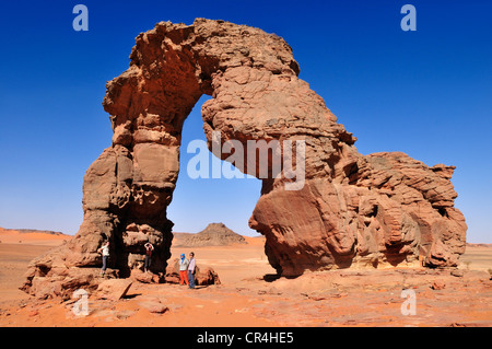 Les touristes sous le pont naturel ou arch rock d'In Tehak, montagnes ou Acacus Tadrart Acacus éventail Banque D'Images