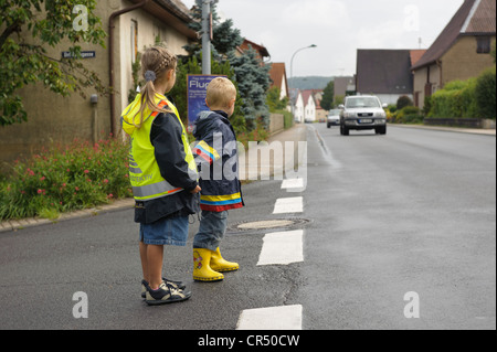 Deux enfants, 3 et 7 ans, l'attente pour traverser la rue, Assamstadt, Bade-Wurtemberg, Allemagne, Europe Banque D'Images