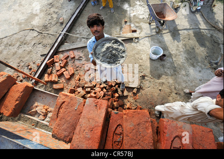 Man lifting pan avec du ciment sur l'échafaudage, la construction de maisons en briques pour les familles dont les maisons ont été détruites pendant la Banque D'Images