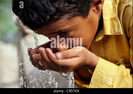 Garçon, 9, de l'eau potable à partir de la pompe d'un puits, village de Motsa Sabgogat Muzaffaragarh, près de Punjab, Pakistan, Asie Banque D'Images