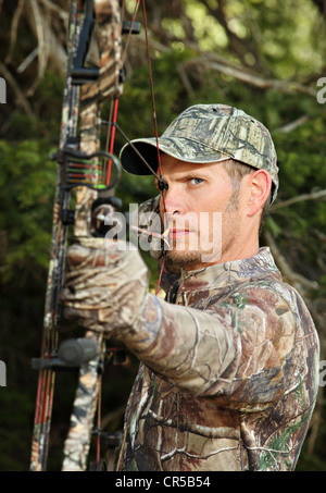 Close-up bow hunter bow tirant une tenue de camouflage retour à Woods Banque D'Images