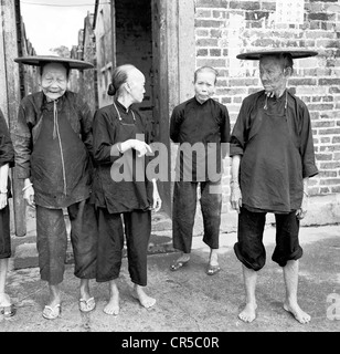 Années 1950. Image historique de la Chine de quatre personnes âgées dames en chinois, avec deux dresss traditionnels circulaire portant des chapeaux. Banque D'Images