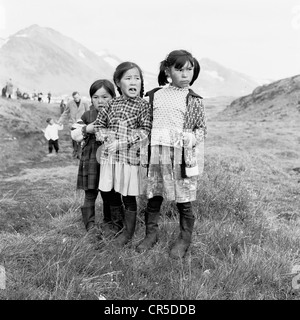 Années 1950. Image historique de trois jeunes Inuits ou Eskimo girls standing ensemble sur une colline herbeuse bank au Groenland. Banque D'Images