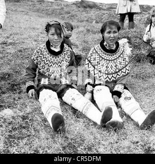 Années 1950. Image historique de deux jeunes filles portant des costumes traditionnels assis sur une colline, dans le Groenland. Banque D'Images