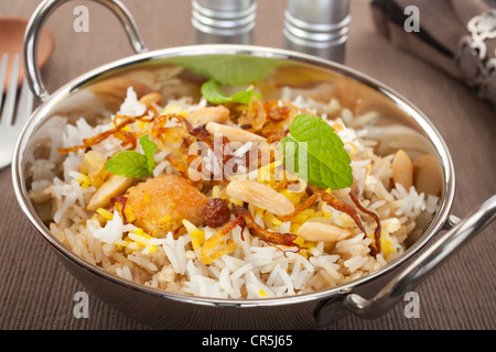 Occasion spéciale indien lave, poulet biryani est garnie avec des oignons frits, des raisins secs, les amandes et la menthe. Banque D'Images