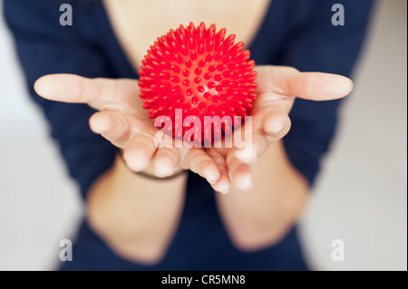 Balle de massage rouge dans les mains d'une femme Banque D'Images