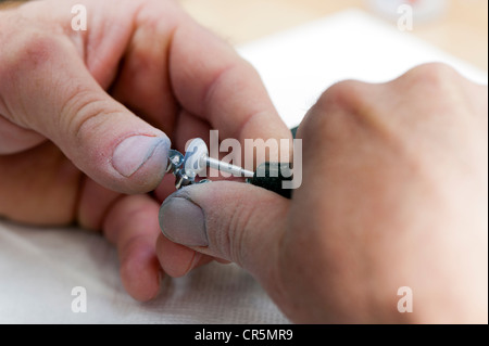 Mains d'un technicien dentaire avec un broyeur et les couronnes métalliques Banque D'Images