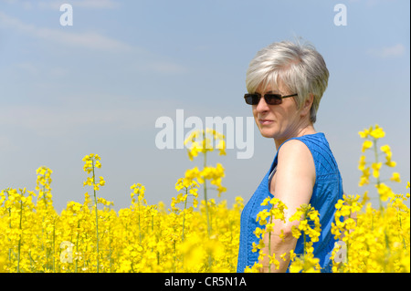 Femme debout dans un champ de canola jaune Banque D'Images