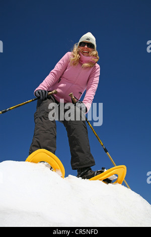 Jeune femme, environ 25 ans, la randonnée en raquettes avec des bâtons, contre un ciel bleu, montagne, forêt de Thuringe Banque D'Images