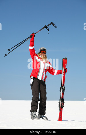 Jeune femme, environ 25 ans, forme avec ses bâtons de ski, contre un ciel bleu, montagne, forêt de Thuringe Banque D'Images