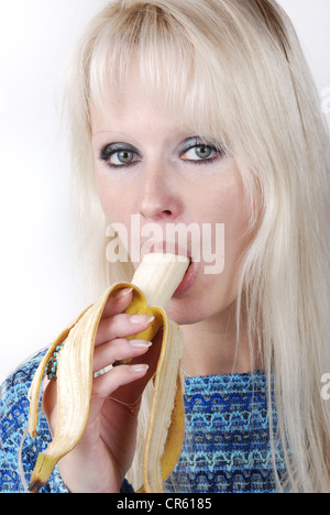 Femme blonde manger une banane Banque D'Images