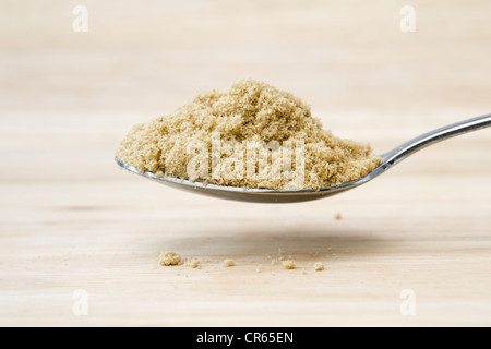 3 cuillère à dessert de sucre brun sur une planche à découper en bois Banque D'Images