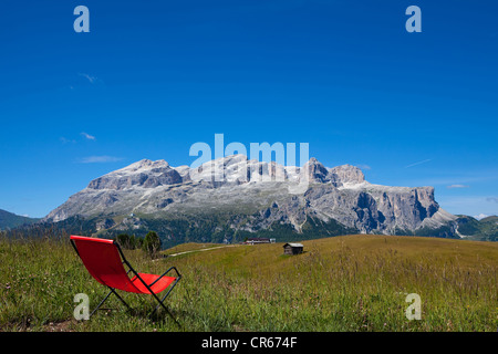 Chaise de jardin rouge dans un pré, vue panoramique sur le groupe du Sella, Dolomites, Tyrol du Sud, Italie, Europe Banque D'Images