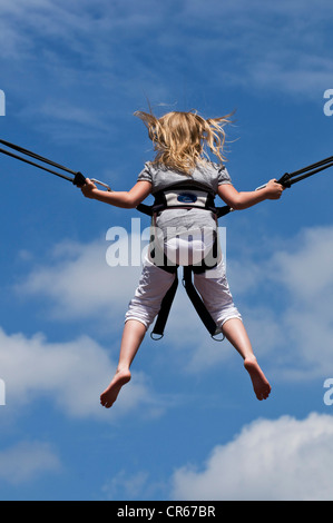 Fille de sauter sur un trampoline avec un harnais de sécurité, face arrière, Nordrhein-Westfalen, Germany, Europe Banque D'Images