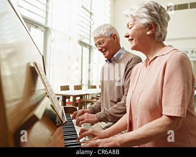 Germany, Cologne, young man playing piano en maison de soins infirmiers Banque D'Images