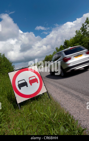 Une voiture passe pas de dépassements à cause d'un mauvais signe d'avertissement sur les gravillons de la route nouvellement refaite uk Banque D'Images
