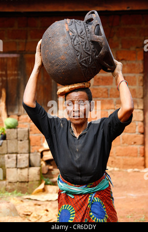 Femme transportant un navire sur sa tête, la production de poterie traditionnelle, Babessi, Cameroun, Afrique Banque D'Images