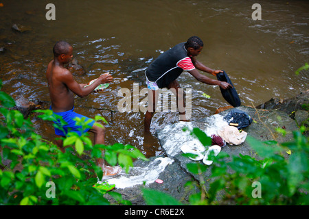 Les jeunes hommes s'en laver les jeans dans un ruisseau, Bamenda, Cameroun, Afrique Banque D'Images