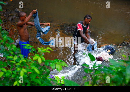 Les jeunes hommes s'en laver les jeans dans un ruisseau, Bamenda, Cameroun, Afrique Banque D'Images