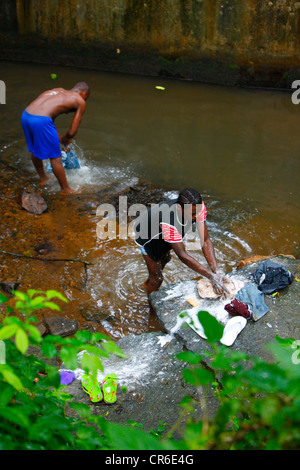 Les jeunes hommes s'en laver les jeans dans un ruisseau, Bamenda, Cameroun, Afrique Banque D'Images