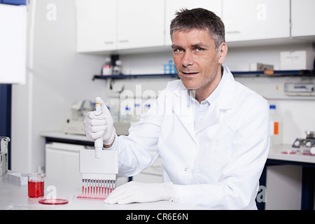 Germany, Bavaria, Munich, chemist liquide rouge à la pipette dans le bac d'essai en laboratoire pour la recherche médicale Banque D'Images