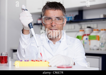 Germany, Bavaria, Munich, chemist liquide rouge à la pipette dans le tube à essai pour la recherche médicale, au laboratoire Banque D'Images