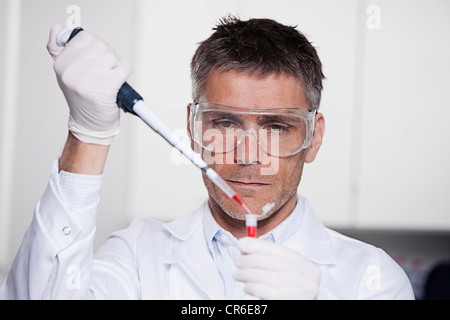 Germany, Bavaria, Munich, chemist liquide rouge à la pipette dans le tube à essai pour la recherche médicale, au laboratoire Banque D'Images