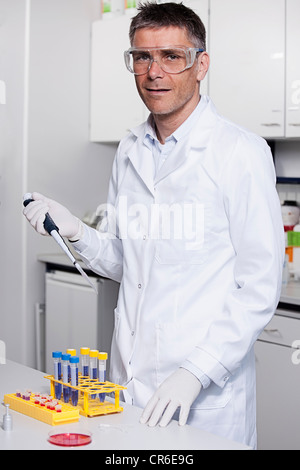 Germany, Bavaria, Munich, chemist liquide rouge à la pipette dans le tube à essai pour la recherche médicale, au laboratoire Banque D'Images