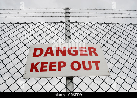 Garder hors de danger signe sur une clôture surmontés de barbelés. Banque D'Images