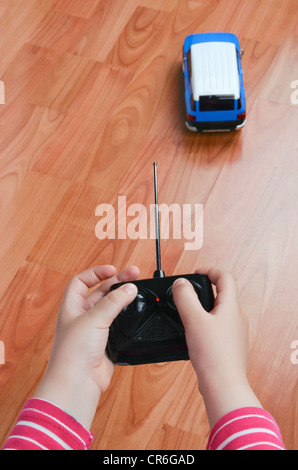 Les mains de l'enfant tenant une petite voiture de contrôle à distance Banque D'Images