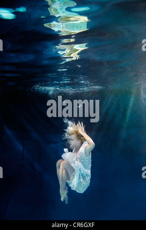 Caucasian woman in dress nager sous l'eau Banque D'Images