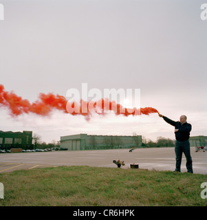 Membre du personnel au sol de l'ingénierie des flèches rouges, la RAF Aerobatic Team, tests de fumée rouge en bouteille d'une procédure normale. Banque D'Images