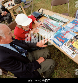 Couple de personnes âgées lire les flèches rouges, la RAF AEROBATIC TEAM au cours des marchandises locales publicv airshow afficher. Banque D'Images