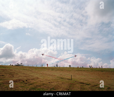 Les flèches rouges, la RAF Aerobatic Team, effectuer leur affichage public sur un talus paysage avec foules ci-dessous. Banque D'Images