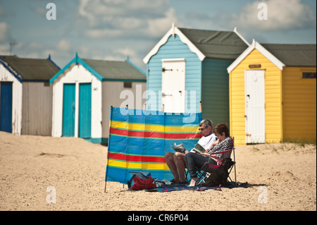 Homme et femme assis sur plage de sable en face de lecture pause vent Banque D'Images