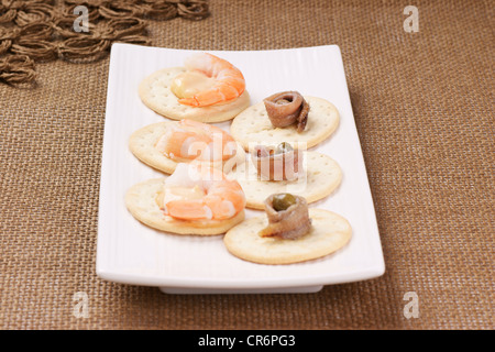 Les crevettes et les anchois apéritif servi sur une plaque blanche. Focus sélectif, peu profonde 6 Banque D'Images